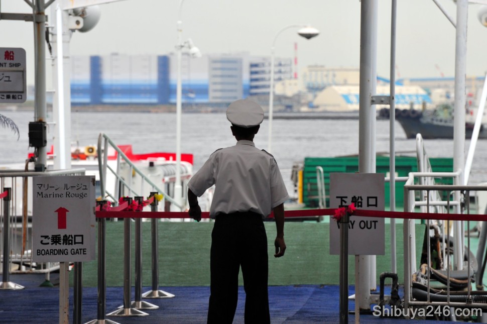 A crew member for the Marine Rouge tourist ship looks out onto the Yokohama Harbor