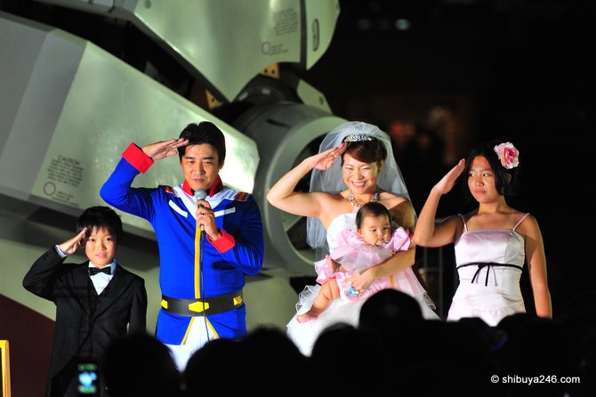 The wedding couple and family salute the crowd