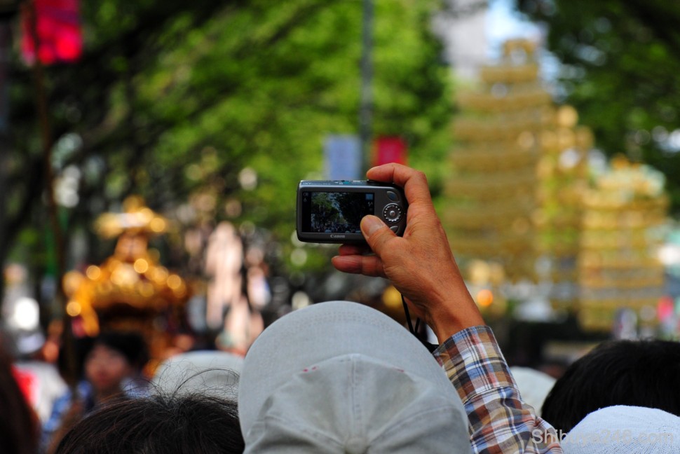 This Canon IXY camera fires off a shot of the parade. There will be plenty of Canons and Nikons at the Games