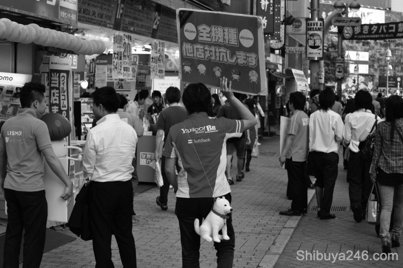 This guy is selling mobiles, softbank and Docomo. The dog is Softbank's mascot. In the commercials he is referred to as Otosan, or father of a rather culturally mixed family